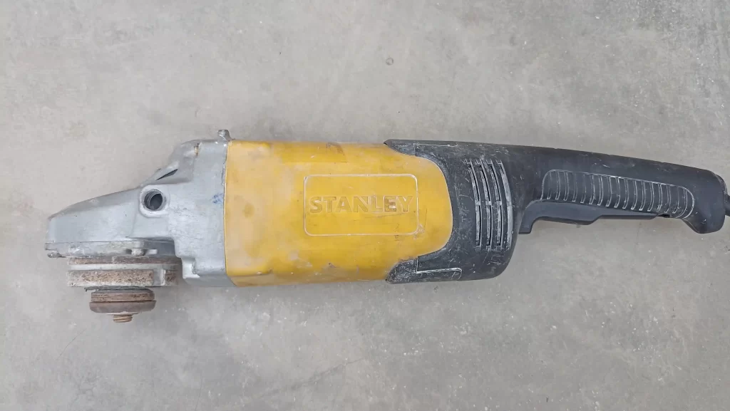 Reparación técnica de amoladora Stanley STGL2223 de 9 pulgadas con herramientas de taller.