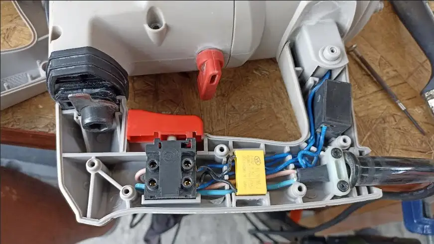 Un técnico midiendo la capacitancia de un condensador de motor con un multímetro digital en un banco de trabajo organizado.