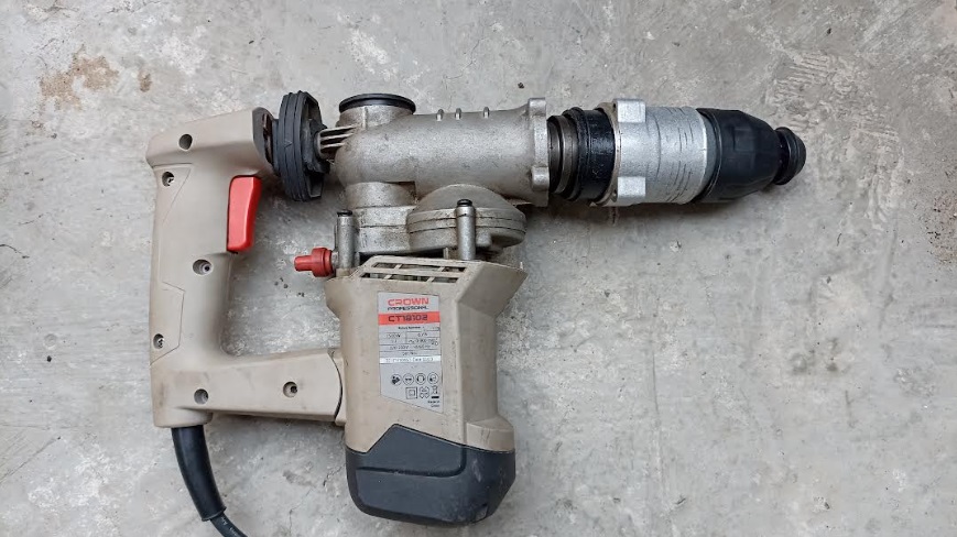 Despiece de un taladro percutor mostrando los engranajes y el mecanismo de impacto desgastado sobre un banco de taller.